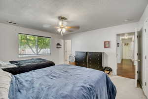 Bedroom with a textured ceiling, a ceiling fan, and carpet flooring