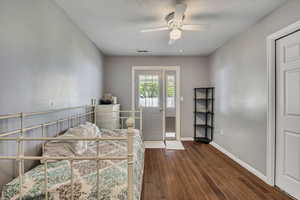 Bedroom featuring dark wood-style floors, baseboards, a textured ceiling, and a ceiling fan