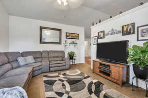 Living area featuring carpet, a ceiling fan, vaulted ceiling, and baseboards