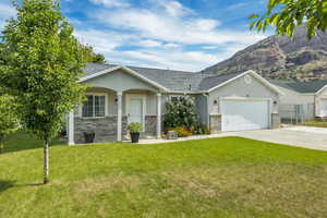 Ranch-style home featuring stucco siding, a garage, driveway, and a front lawn