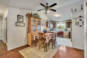 Dining room with wood finished floors, a ceiling fan, lofted ceiling, and baseboards
