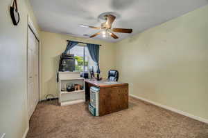 Office area with a ceiling fan, carpet, baseboards, and a textured ceiling