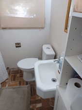 Bathroom with brick floors, a sink, and toilet