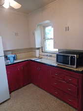 Kitchen with stainless steel microwave, freestanding refrigerator, decorative backsplash, arched walkways, and ceiling fan