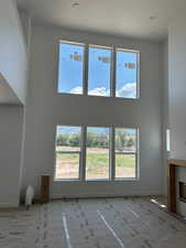 Unfurnished living room featuring a towering ceiling, plenty of natural light, a fireplace, and baseboards