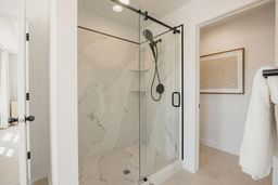 Bathroom with a marble finish shower and baseboards