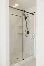 Full bath with a marble finish shower