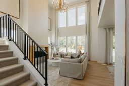 Living area with a chandelier, stairway, wood finished floors, and a high ceiling