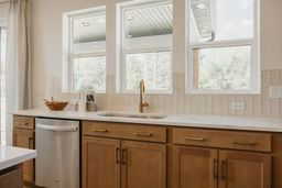 Kitchen featuring dishwasher, brown cabinets, light countertops, and a sink