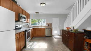 Kitchen with appliances with stainless steel finishes, a sink, backsplash, and a kitchen breakfast bar