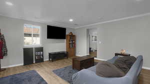 Living room with ornamental molding, wood finished floors, healthy amount of natural light, baseboards, and recessed lighting