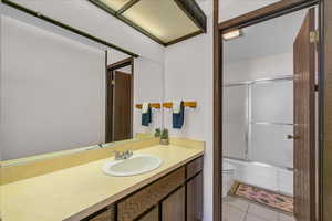 Bathroom featuring toilet, vanity, combined bath / shower with glass door, and tile patterned floors