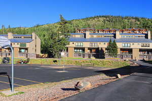 View of property with uncovered parking and a forest view