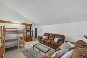 Bedroom with carpet, vaulted ceiling, and a textured ceiling