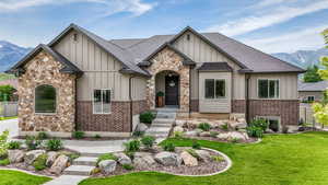 View of front of house with board and batten siding, a mountain view, stone siding, and a shingled roof