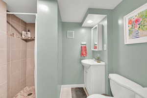 Full bathroom with vanity, tile patterned flooring, toilet, tiled shower, and baseboards