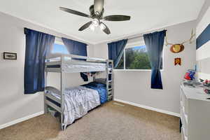 Carpeted bedroom with baseboards and a ceiling fan