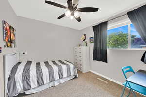 Carpeted bedroom with ceiling fan and baseboards