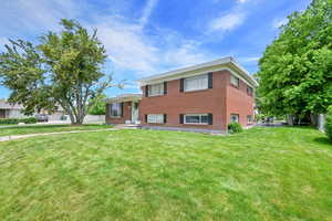 Tri-level home with a front yard and brick siding
