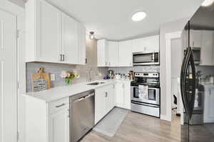 Kitchen featuring stainless steel appliances, a sink, tasteful backsplash, and light countertops