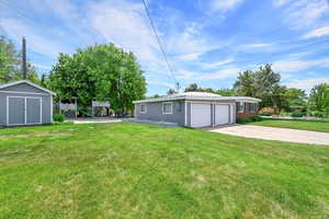 View of grassy yard with driveway and a garage