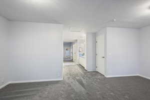 Carpeted empty room with attic access, baseboards, and a smoke detector