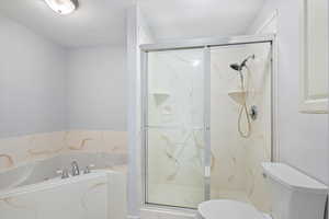 Full bath with toilet, a bath, and a marble finish shower
