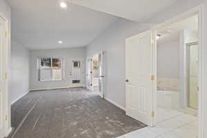 Interior space featuring lofted ceiling, recessed lighting, baseboards, carpet floors, and tile patterned floors