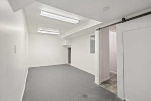 Finished below grade area with baseboards, electric panel, and a barn door