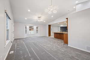 Unfurnished living room with vaulted ceiling, baseboards, light carpet, recessed lighting, and a chandelier