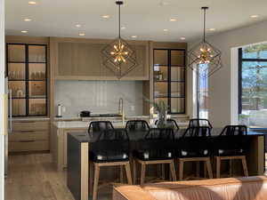 Kitchen with a chandelier, recessed lighting, light countertops, decorative backsplash, and light wood-style flooring