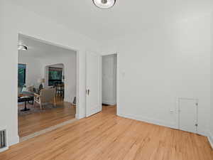Unfurnished room featuring arched walkways, wood finished floors, and baseboards