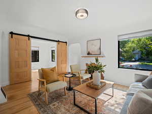 Living room with a barn door, light wood-type flooring, and baseboards
