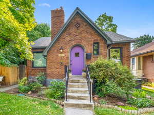English style home featuring a chimney, brick siding, central AC, and a shingled roof