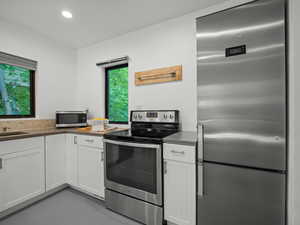 Kitchen featuring appliances with stainless steel finishes, white cabinetry, recessed lighting, and dark countertops