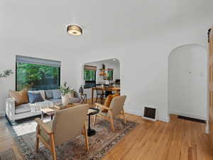 Living area featuring arched walkways, light wood-style flooring, and baseboards