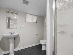 Full bath featuring toilet, a stall shower, baseboards, and tile patterned flooring