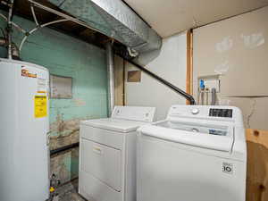 Laundry room with water heater, washer and dryer, and concrete block wall