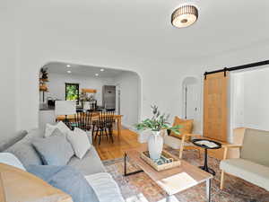 Living room featuring arched walkways, light wood-style floors, a barn door, recessed lighting, and baseboards