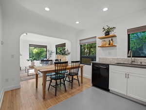 Kitchen with black dishwasher, a sink, white cabinets, healthy amount of natural light, and recessed lighting