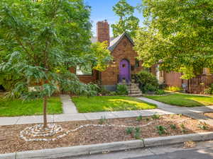 Tudor house with brick siding, a front yard, and a chimney