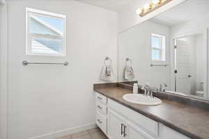 Bathroom featuring vanity, toilet, tile patterned floors, and baseboards