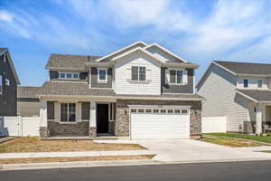 Craftsman house featuring concrete driveway, a garage, stone siding, covered porch, and roof with shingles