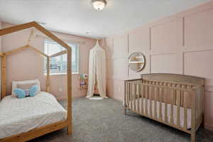 Bedroom featuring carpet floors, a decorative wall, and baseboards