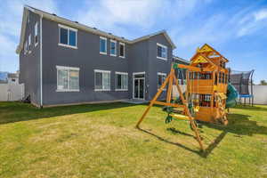 Back of property with a trampoline, a playground, and stucco siding