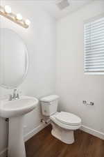 Bathroom with toilet, wood finished floors, baseboards, and a sink
