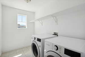 Laundry area with washer and dryer, baseboards, and light tile patterned floors
