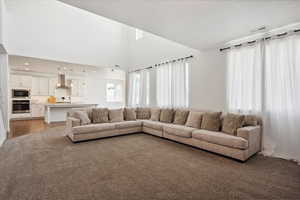 Living area featuring plenty of natural light, light wood-style floors, a towering ceiling, light carpet, and recessed lighting