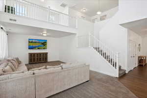 Living area featuring stairs, a towering ceiling, baseboards, and wood finished floors
