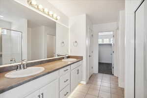 Bathroom with tile patterned flooring, double vanity, a stall shower, and baseboards